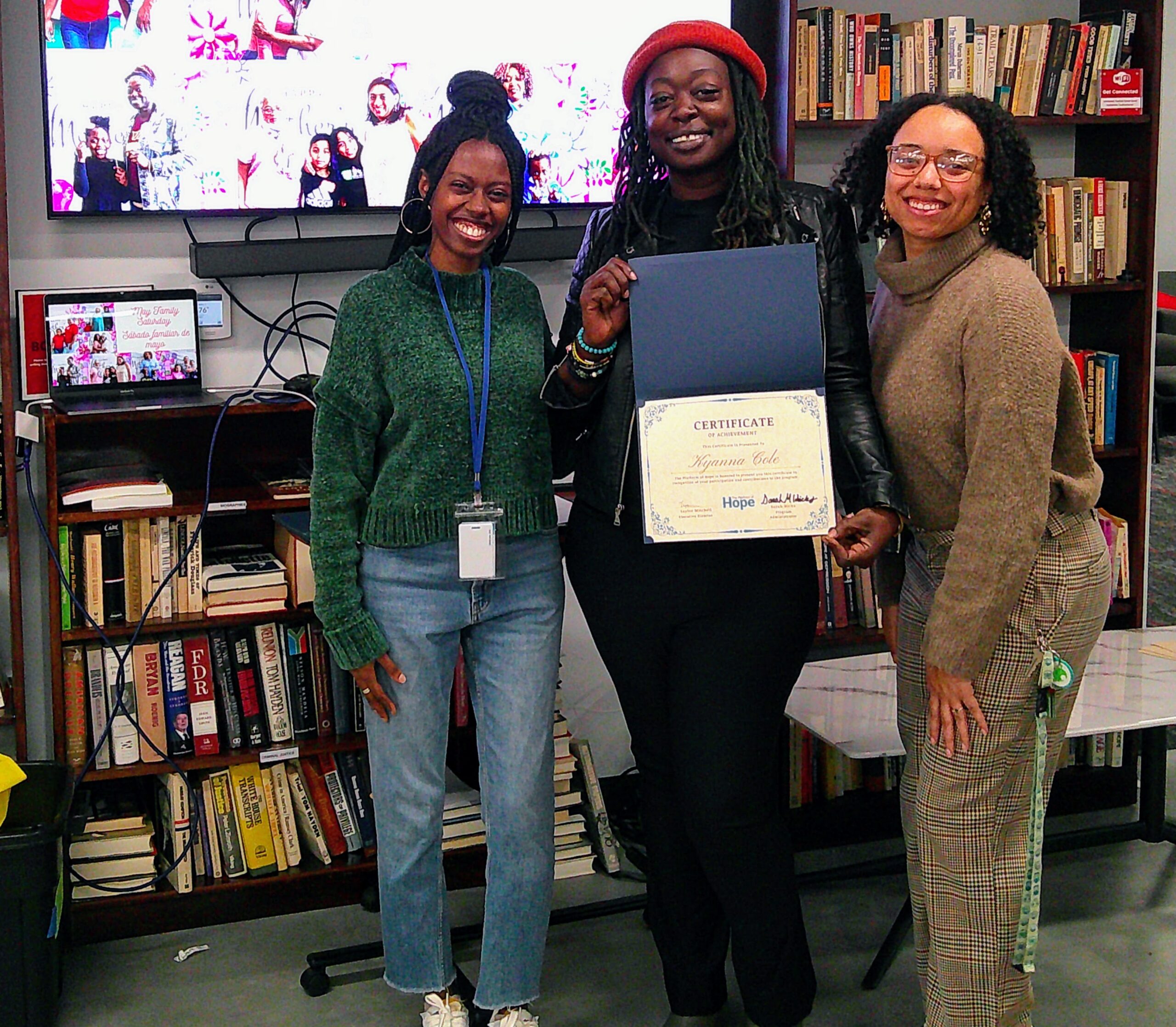 A Platform of Hope family celebrating an achievement certificate with staff